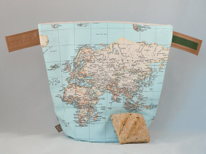 Bunbag „Traveller“: Brötchentasche mit Weltkarte, offen, davor ein Brötchen