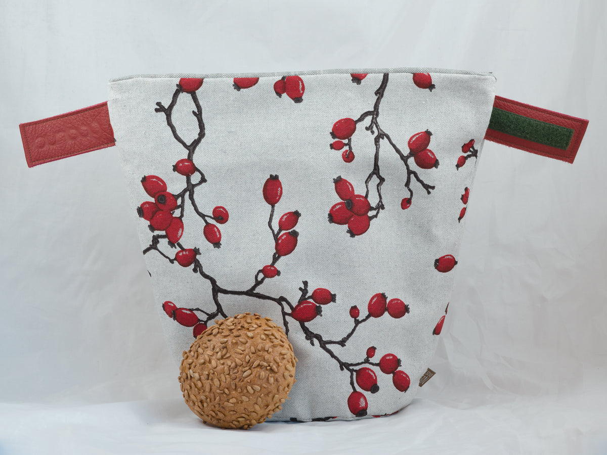 Bunbag „Rose Hip“: Brötchentasche mit Hagebuttenzweigen, offen, davor ein Brötchen