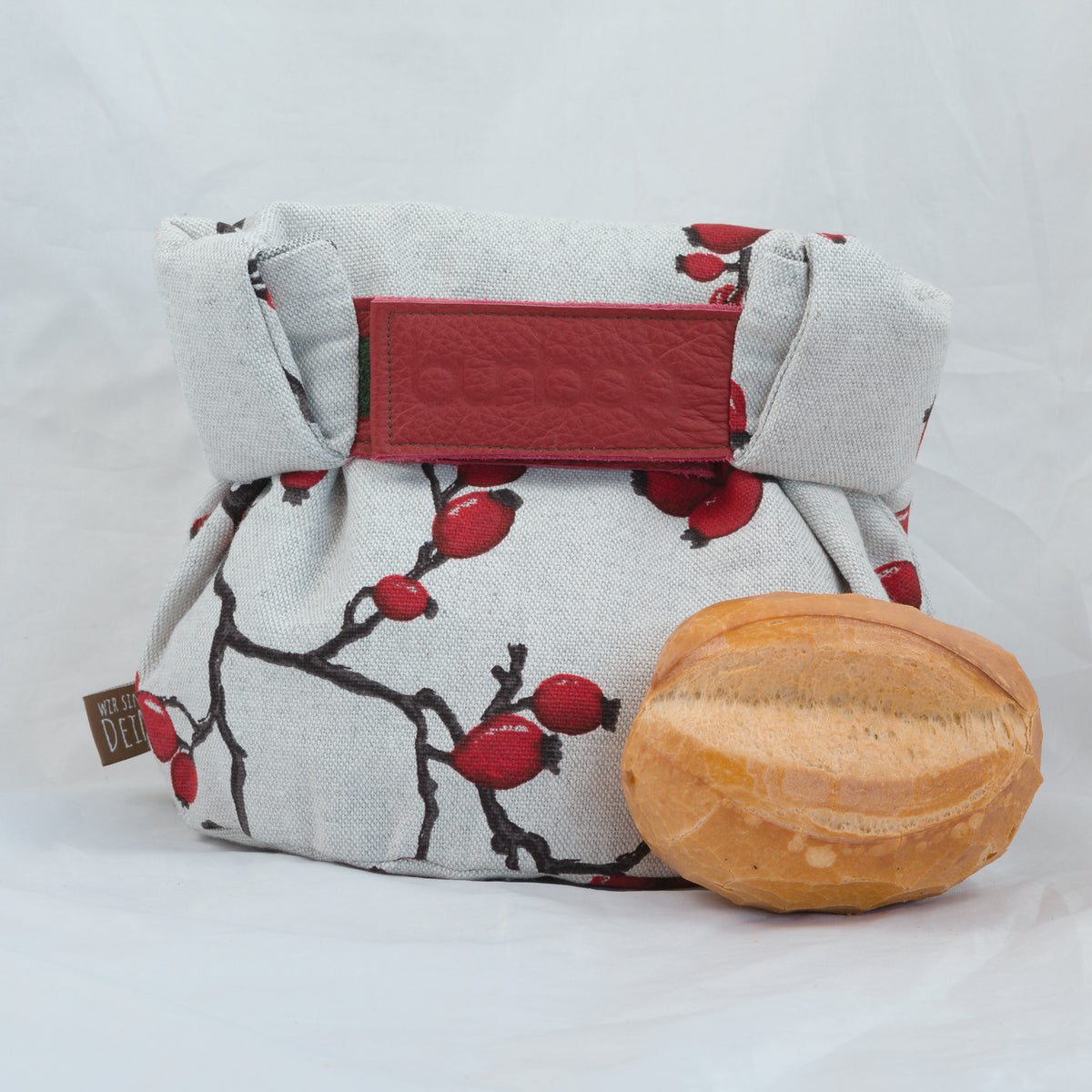 Bunbag „Rose Hip“ geschlossen mit roter Lasche, davor ein Brötchen
