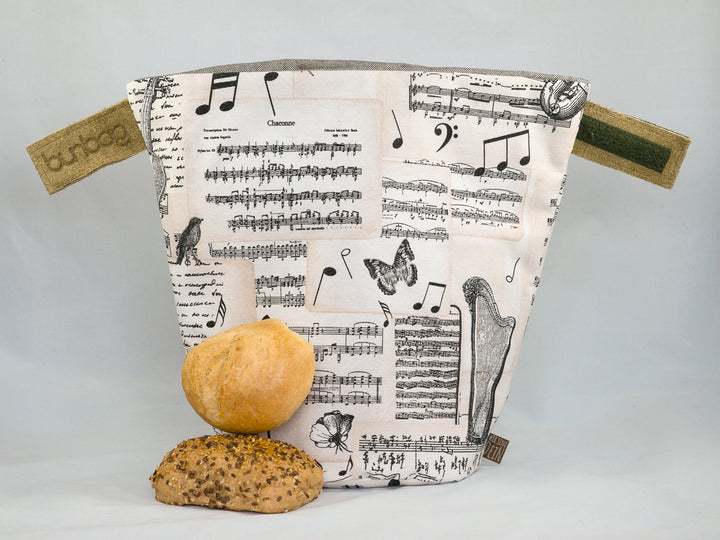 Bunbag „Bella Musica“: Brötchentasche mit Noten und Instrumenten, offen, davor Brötchen