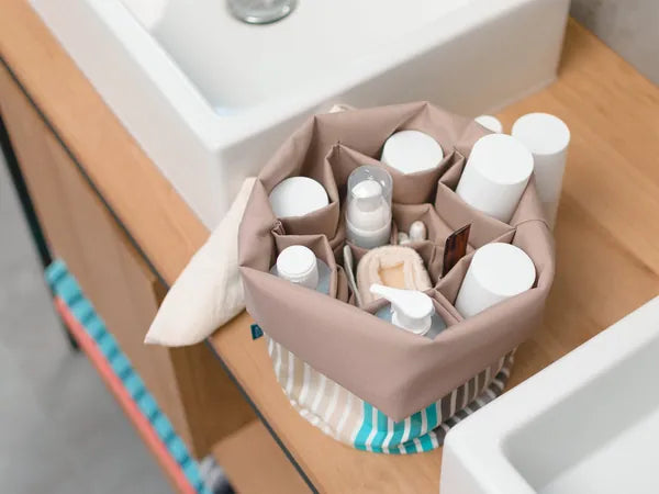 Geöffneter Beaubag mit Pflegeprodukten in den Fächern auf dem Waschtisch